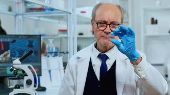 Mature Man Lab Technician Looking at Virus Sample