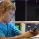 Blonde boy uses smartphone while surfing the internet in cafe - VideoHive Item for Sale