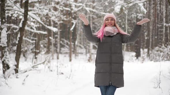 Slow Motion, a Woman in a Jacket Hat and Scarf in the Winter in the Forest Holding Snow in Her Hands