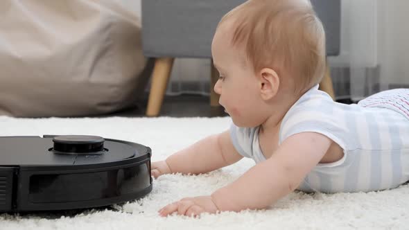 Closeup of Little Baby Boy Looking on Rotating Brushes of Robot Vacuum Cleaner