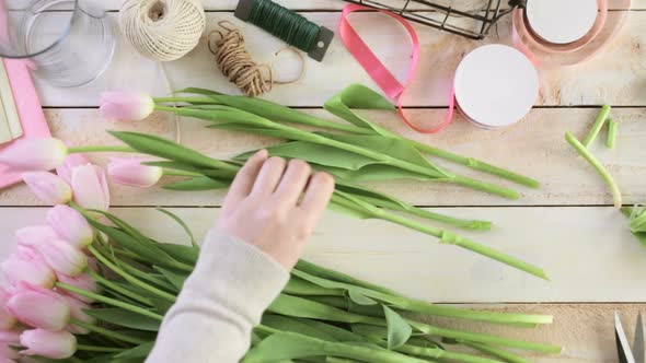 Step by step. Florist wrapping pink tulips in bouquet.