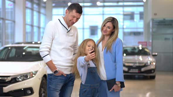 Live Camera Zoom in to Happy Girl Showing Car Key Smiling Standing with Mother and Father in Car