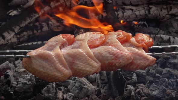 Closeup of Raw Chicken Wings Pierced with the Skewers and Fryed Above the Fire