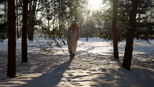 A Man in Warm Winter Clothes Walks Through a Winter Forest on a Sunny Day