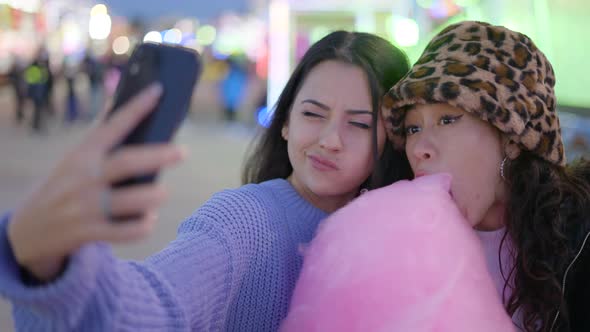 Lovely Female Couple Shoot Selfies with Phone Eating Candy Floss and Making Funny Faces in Amusement