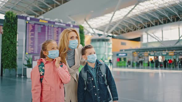 Mother and Children Wearing Protective Medical Masks Standing at Airport Building and Enjoying