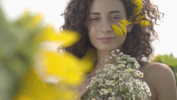 Portrait of a Confident Beautiful Curly Girl Looking at the Camera Smiling Standing in the Sunflower