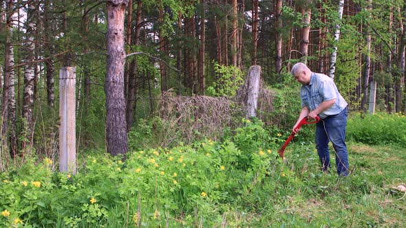 A Dexterous Man Mows Tall Green Grass with an Electric Trimmer