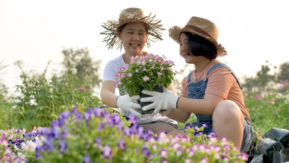 Slow motion Happy Asian mother and daughter planting flower together in the garden.