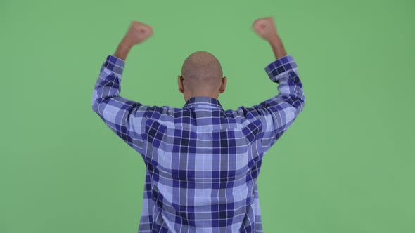 Rear View of Happy Bald Hipster Man with Fists Raised