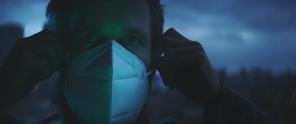 Man taking off his medical mask and putting his hand on a window