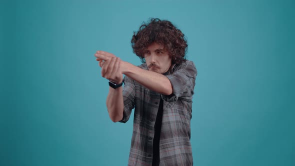 Charismatic Hipster Imitates a Pistol with His Hands and Shoots in Front Dressed in a Plaid Shirt