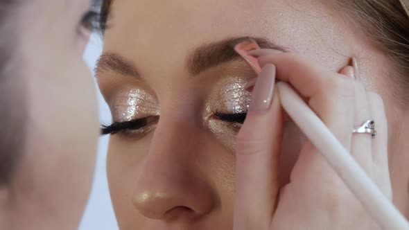 A Professional Makeup Artist with a Special Brush Corrects and Paints the Shape of the Eyebrows of a
