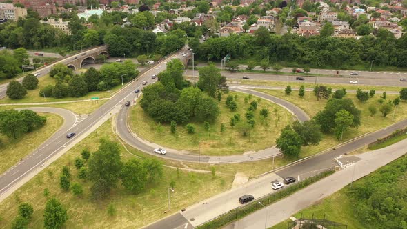 A bird's eye view over a parkway exit on a cloudy day. The drone orbits the circular exit in a count