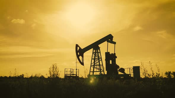 Silhouette of Working Oil Pump From Oil Field at Sunset. The Industrial Equipment.