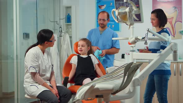 Little Girl Patient with Tooth Pain Explaining Dental Problem To Pediatric Dentist
