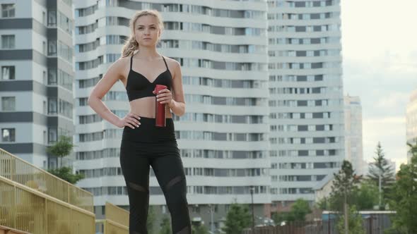 Young Sports Woman Drinks Water From a Metal Bottle