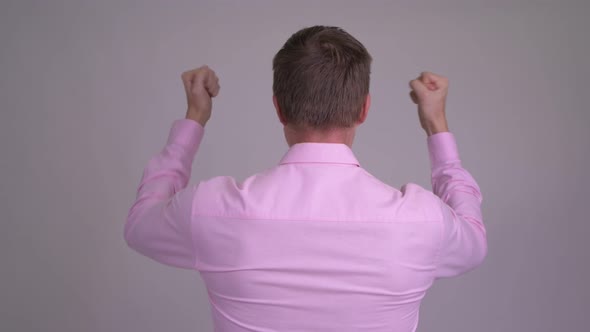 Rear View of Young Businessman Looking Excited with Fists Raised