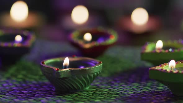 Lit candles in decorative clay pots on woven table mat, focus on foreground, bokeh background