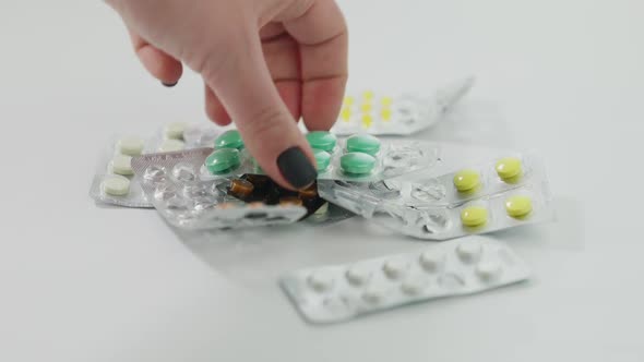 Closeup Pill Blisters Lying on White Table with Female Hand Taking Medication Leaving