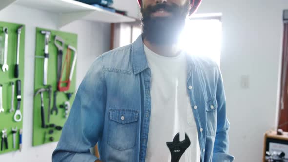 Portrait of mechanic standing with work tool in workshop