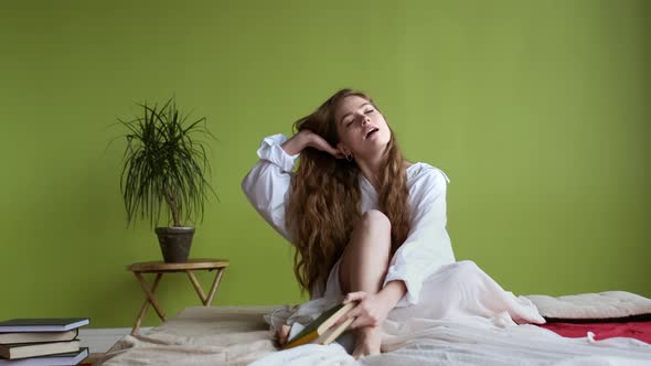 Girl Sitting On The Bed And Reading Book.