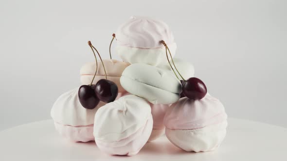 Coloured Marshmallows and Cherry at Plate Rotation Over White Background