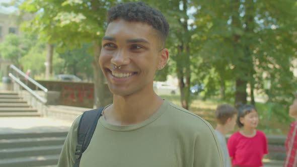 Portrait of Charming Black Male Student Looking with Cheerful Smile Outdoor