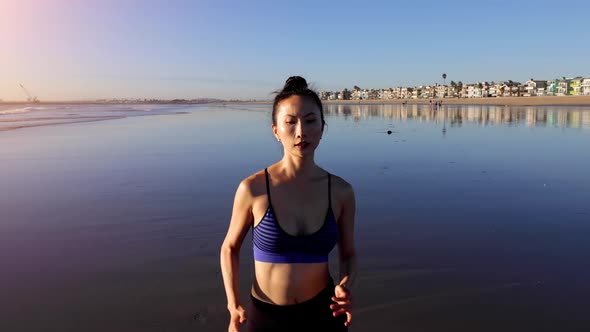 Slow motion shot of an Asian woman jogging on the beach