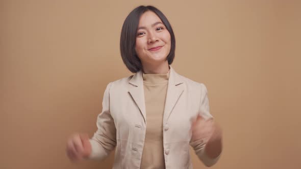 Asian business woman happy smiling and showing thumb up isolated over beige background. 4K video