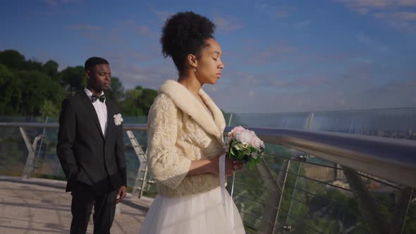 Sad African American Bride in Beautiful Wedding Dress Looking Back at Groom and Turning to Camera