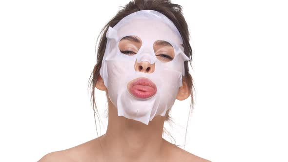 Funny Caucasian Girl with Facial Mask Making Faces Over White Background in Slowmotion