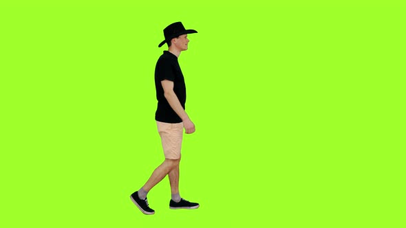 Casual Man in Black T-shirt and Cowboy Hat Walks on Green Background