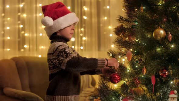 Happy Smiling Boy Decorating Christmas Tree with Red Bauble