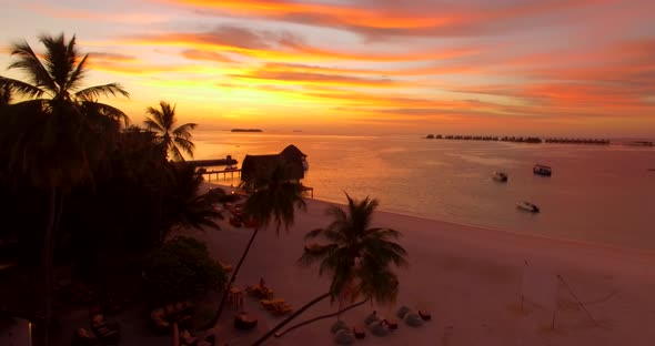 Aerial drone view of a scenic tropical island in the Maldives at sunset.