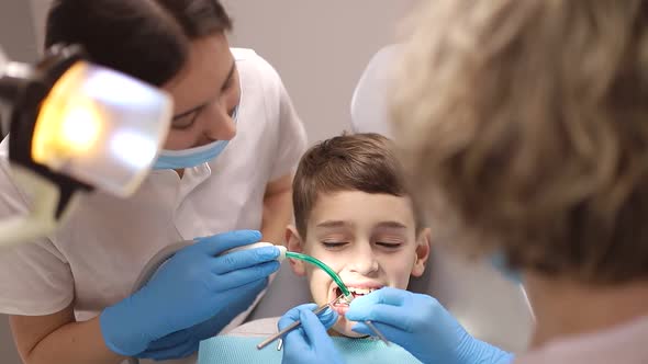 A little boy treats his teeth, two dentists examine the child's teeth, concepts about dentistry