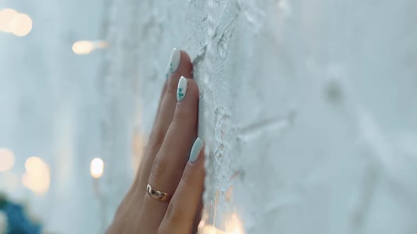 Girl Touches the Wall with a Hand, Among Small Lamps, Close-up