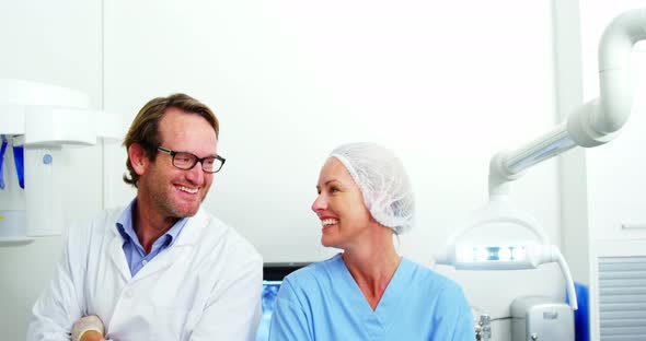 Smiling dentist and dental assistant standing with arms crossed