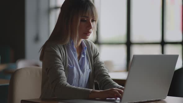 Young Asian Attractive Female Office Worker Sitting at the Laptop Computer at the Desk Working and