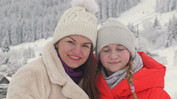 Family Portrait of a Young Woman with Her Teenage Daughter on the Background of a Winter Landscape