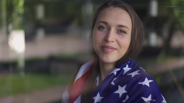 Closeup Young Brunette Woman Wrapping in American Flag Smiling Looking at Camera