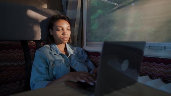 African Female Freelancer Working at a Laptop While Sitting in a Car Typing Text and Remote Work in