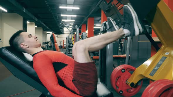 A Man Is Using a Fitness Machine To Build His Legs