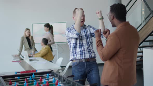 Young business partners making handshake in an office while their team working in the background