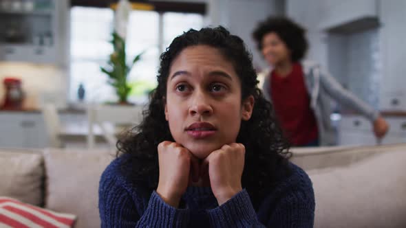 Mixed race woman sitting on couch and looking annoyed