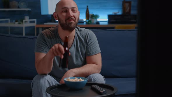 Man Sitting on Cozy Couch in Living Room Alone Eating Popcorn Drinking Beer