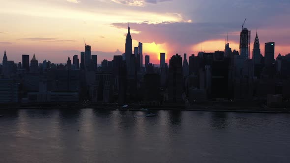 a slow pan left at sunset over New York City's east river, placing the sun between two buildings