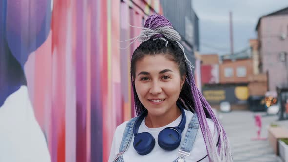 Joyful Mixedrace Girl in with Dreadlocks and Headphones Walking and Turning Back Looking at Camera