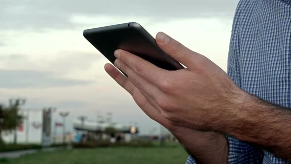 Man Clicks on a Digital Tablet at Sunset