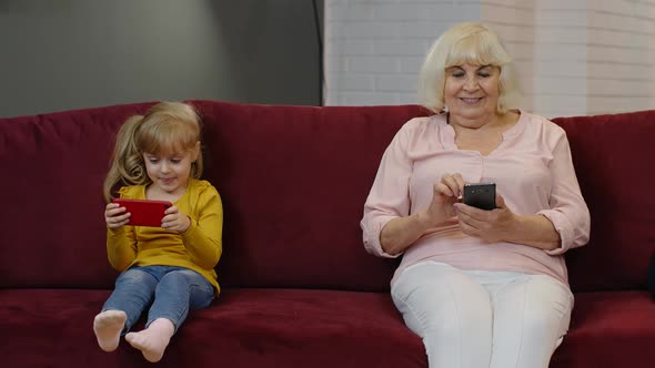 Senior Grandmother with Child Girl Granddaughter Using Digital Mobile Phone, Playing Games at Home